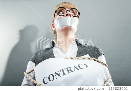 Businesswoman bound by contract with taped mouth. 133823401