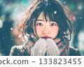A young woman with dark hair wearing a scarf standing in the snow 133823455