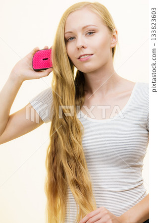 Blonde girl brushing her long hair 133823603