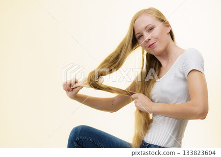 Blonde girl brushing her long hair 133823604