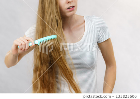 Woman combing long healthy blonde hair 133823606