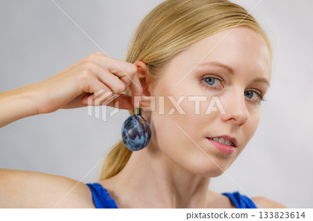 Girl holds plum fruit to her ear 133823614