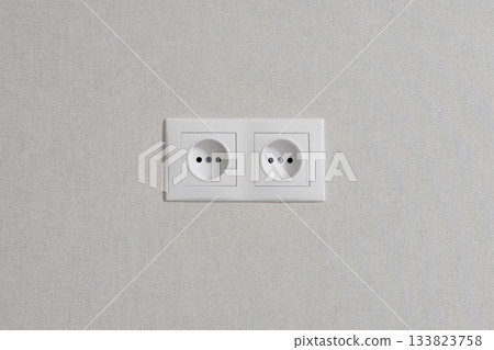 Two white outlets are on a white wall. Two white outlets are on a white wall. 133823758