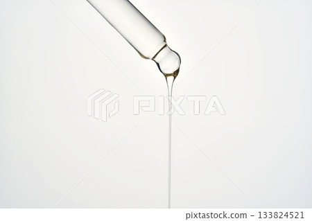 Cosmetic pipette dropping liquid serum oil on white background Cosmetic pipette dropping liquid serum oil on white background 133824521