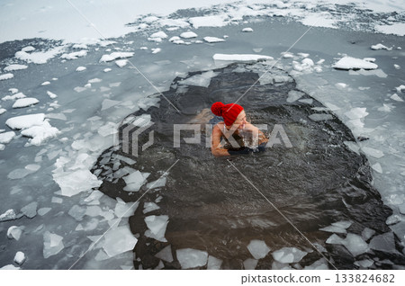 Elderly woman practicing outdoor ice bathing during winter season 133824682