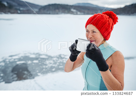 Older woman enyoing hot tea after ice bathing in lake. 133824687