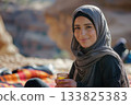 An athletic Arabic woman takes a rejuvenating break from her outdoor workout in sunny Jordan, sipping fasting tea. Strength, serenity, and wellness meet under the bright desert sun. 133825383