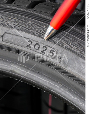 Close-up of tire date code with pen pointing to week and year marking on rubber sidewall Close-up of tire date code with pen pointing to week and year marking on rubber sidewall 133825449