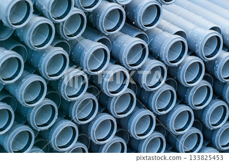 Stacked PVC pipes with water droplets ready for installation at construction or plumbing site 133825453