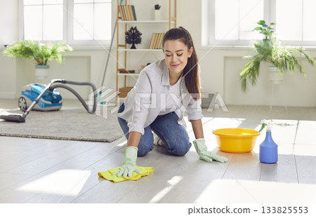 Positive Woman Dusting the Living Room Floor at Home 133825553