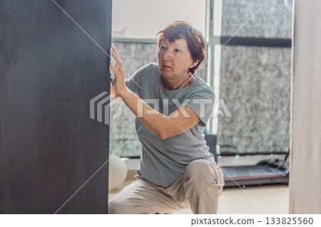 Elderly woman cleaning her home, organizing and tidying up with care in a bright living space. Concept of active aging, independence, daily routine, healthy lifestyle, and maintaining a comfortable 133825560