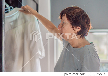 Elderly woman cleaning her home, organizing and tidying up with care in a bright living space. Concept of active aging, independence, daily routine, healthy lifestyle, and maintaining a comfortable 133825564