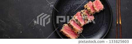 Seared grilled tuna steak tataki slices sesame seeds lemon black plate healthy delicacy space for text Seared grilled tuna steak tataki slices sesame seeds lemon black plate healthy delicacy space for text 133825603