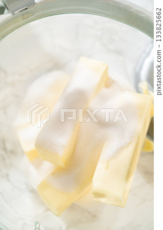 Butter sticks coated with sugar in a glass bowl, ready to be creamed for Easter Cookie Sandwich with Raspberry Buttercream. A simple yet beautiful moment in baking prep. 133825662