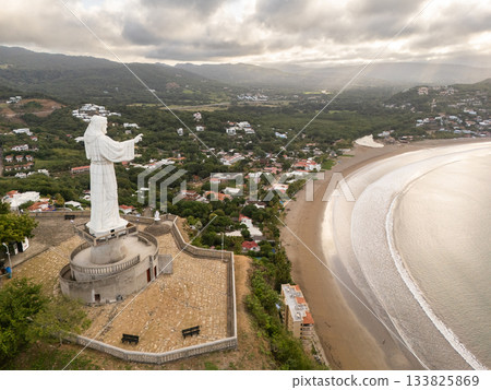 View of a large statue overlooking a coastal town at sunset View of a large statue overlooking a coastal town at sunset 133825869