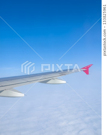 airplane wing over cloud sea, red wingtip, high-altitude view 133825961