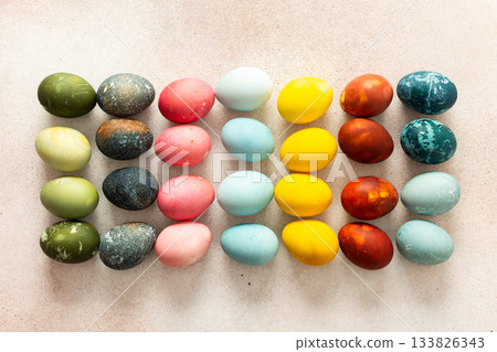 Dozens of beautifully colored Easter eggs in bright shades of green, pink, yellow, blue, and red are arranged in neat rows on a light background, ready for holiday festivities Dozens of beautifully colored Easter eggs in bright shades of green, pink, yellow, blue, and red are arranged in neat rows on a light background, ready for holiday festivities 133826343