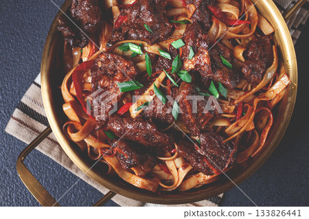 Udon noodles with beef in Mongolian style, with green onions and vegetables, homemade, on a dark background, Udon noodles with beef in Mongolian style, with green onions and vegetables, homemade, on a dark background, 133826441