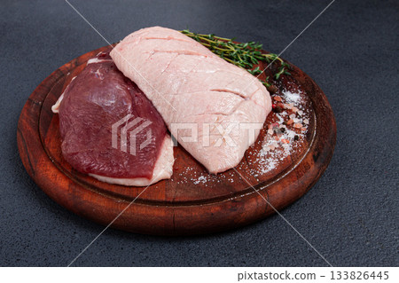 Fresh raw duck breasts, on a wooden chopping board, with herbs and spices, no people 133826445