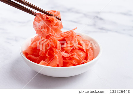 Pickled ginger, with chopsticks, in a small white bowl, on a marble countertop, close-up, no people, 133826448