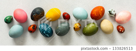 Various Easter eggs in vibrant colors and patterns are neatly arranged, showcasing the joy and creativity associated with spring celebrations and family gatherings, banner 133826513