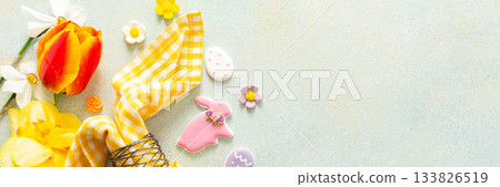 Bright spring flowers surround a beautifully set table with pastel Easter eggs, candy, and decorative elements, capturing the spirit of the holiday atmosphere, banner Bright spring flowers surround a beautifully set table with pastel Easter eggs, candy, and decorative elements, capturing the spirit of the holiday atmosphere, banner 133826519