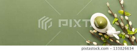 Festive Easter decorations include a cute bunny figurine, colorful egg, and delicate spring branches, creating a cheerful atmosphere perfect for the holiday, banner 133826634