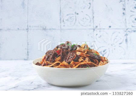 Udon noodles with Mongolian beef, green onions and vegetables, in a white plate, on a light background, homemade, no people, Udon noodles with Mongolian beef, green onions and vegetables, in a white plate, on a light background, homemade, no people, 133827160