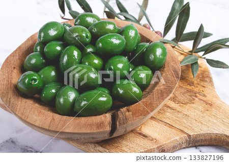 Halkidiki olives, classic Greek green olives, in a wooden bowl, on a cutting board, top view, without people, Halkidiki olives, classic Greek green olives, in a wooden bowl, on a cutting board, top view, without people, 133827196