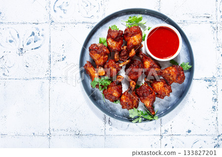 Crispy pieces of fried chicken, on a plate with sauce and herbs, in a modern kitchen environment, there are no people Crispy pieces of fried chicken, on a plate with sauce and herbs, in a modern kitchen environment, there are no people 133827201