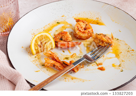 the remains of fried shrimp in oil with spices, on a white plate, with a fork, there are no people, the remains of fried shrimp in oil with spices, on a white plate, with a fork, there are no people, 133827203