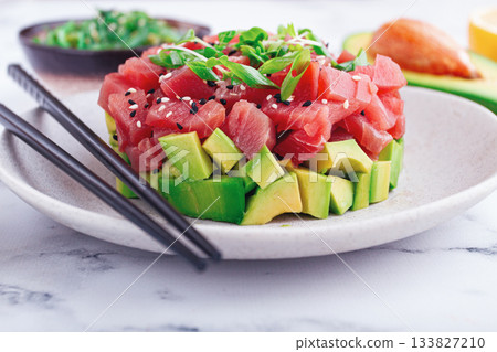 Fresh tuna tartare with avocado served on a marble table with soy sauce and seaweed salad Fresh tuna tartare with avocado served on a marble table with soy sauce and seaweed salad 133827210