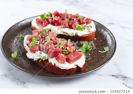 sandwiches, rye bread with cream cheese, sliced tuna fillet with herbs, breakfast on a black plate, homemade, 133827214