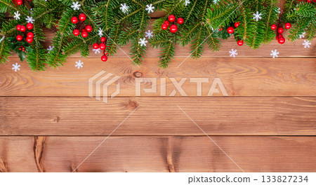 Natural Christmas border with fir branches and red holly berries on wooden background 133827234