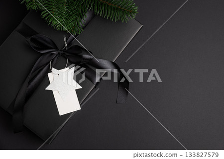 Black Christmas Gift Box with Satin Ribbon and White Blanck Label on Dark Holiday Background 133827579