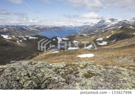 Stunning view of Lake Bygdin surrounded by rugged mountains and scenic landscapes in Jotunheimen National Park, Norway 133827996