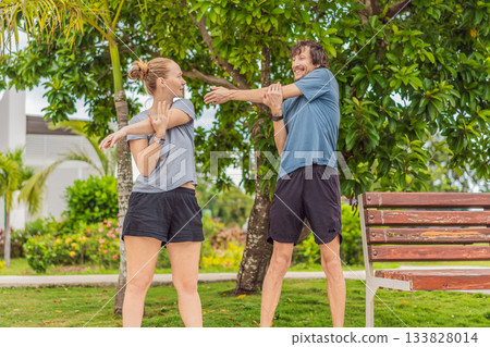 A man and woman working out together in a sunny park, staying active and motivated as a team. Outdoor fitness, wellbeing, healthy lifestyle, exercise routine and relationship bonding concept 133828014