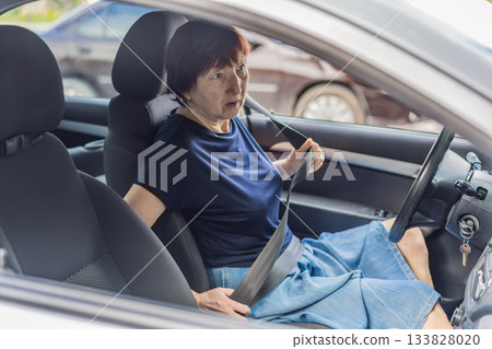 Older woman driving a car with focus and confidence on a bright day. Real lifestyle moment representing independence, mobility, freedom, active aging, transportation and modern everyday life for 133828020