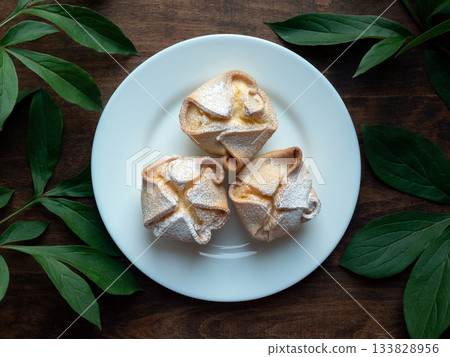 Italian soffioni pastries on white plate, top view. Sweet ricotta-filled treats dusted with powdered sugar 133828956
