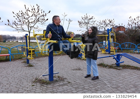 father and daughter walking in the park Outdoor sports ground. Free exercise equipment in public places. father and daughter walking in the park Outdoor sports ground. Free exercise equipment in public places. 133829454