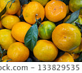 Orange tangerines with green leaves on the store shelf. 133829535