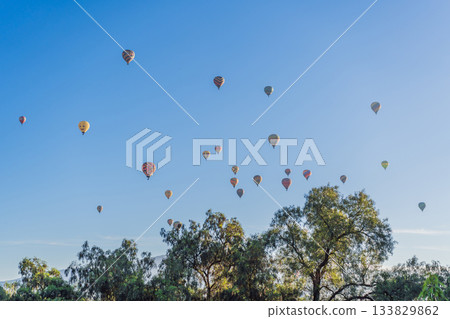Colorful hot air balloons floating over Teotihuacan in Mexico, creating a breathtaking view of the ancient pyramids. Tourism, adventure, and cultural heritage concept Colorful hot air balloons floating over Teotihuacan in Mexico, creating a breathtaking view of the ancient pyramids. Tourism, adventure, and cultural heritage concept 133829862