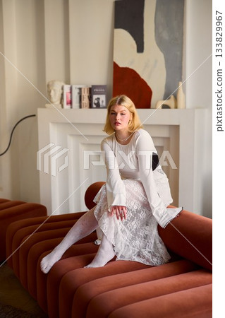 Fashionable fairhaired woman posed gracefully on sofa chair Fashionable fairhaired woman posed gracefully on sofa chair 133829967