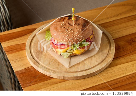 Rustic sandwich on natural setting, Traditional beef burger with fresh ingredients displayed Rustic sandwich on natural setting, Traditional beef burger with fresh ingredients displayed 133829994