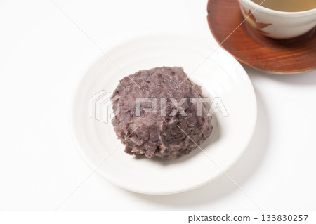 白盤子裡盛著飯糰和茶。 133830257