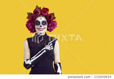 Portrait of young woman with sugar skull makeup pointing with her finger to side 133830654