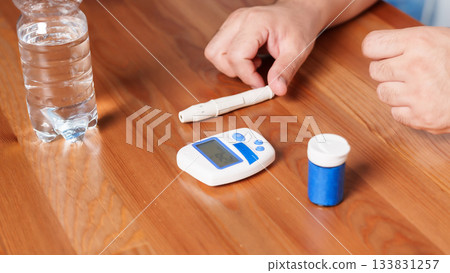 4K close-up of a glucometer lying on a table with diabetes testing accessories. Clean minimalistic setup, soft medical lighting, and a clear healthcare atmosphere. Concept of blood glucose monitoring 133831257