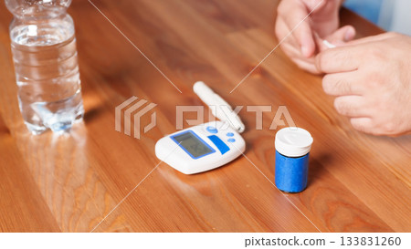4K close-up of a glucometer lying on a table with diabetes testing accessories. Clean minimalistic setup, soft medical lighting, and a clear healthcare atmosphere. Concept of blood glucose monitoring 133831260
