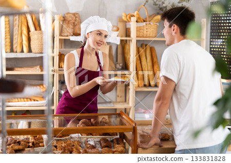 Young woman seller gives customer order, girl serves customers guy in bakery. 133831828