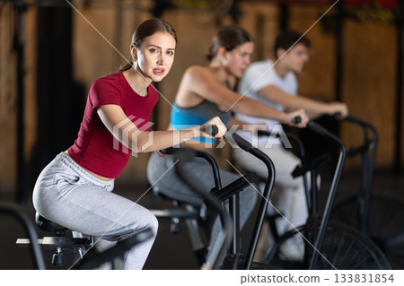Focused girl works out with airbike during class at fitness club 133831854